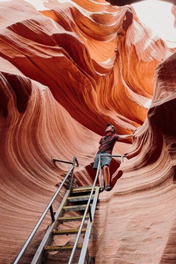 Ron standing at the top of stairs looking at the wavy walls inside lower antelope canyon