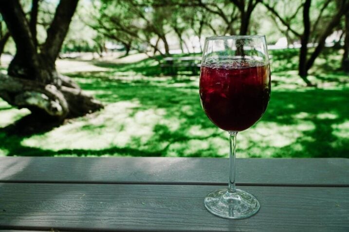 a glass of sangria with a background of green gras at the oak creek vineyard which is a great stop on. a sedona wine tours 