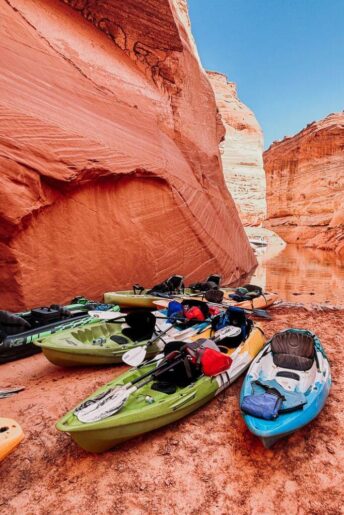 numerous kayaks parked on a desert beach at the mouth of antelope canyon