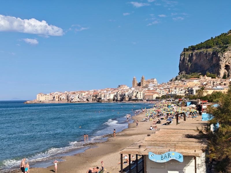 Cefalù, Italy - A sandy bay beneath a looming rocky promontory